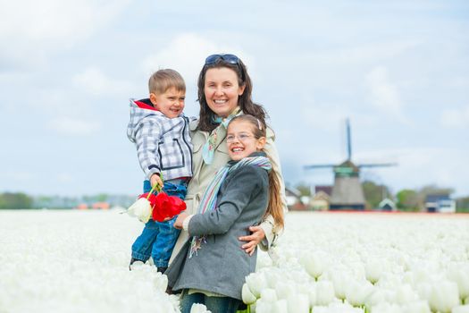 Mother with her child walks between of the white tulips field