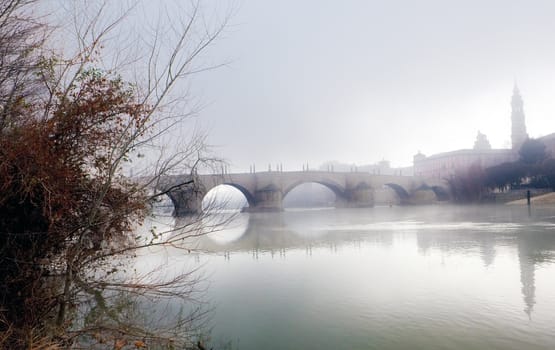Foggy winter landscape with river and bridge