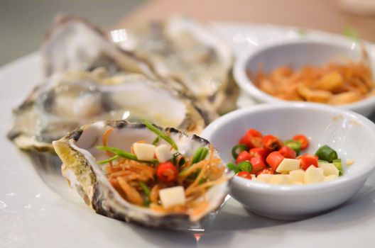 Oysters  with chilli and fried garlic , on white plate