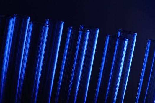 Glass chemistry tubes on a colour background