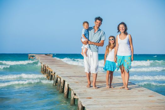 Family of four on wooden jetty by the ocean