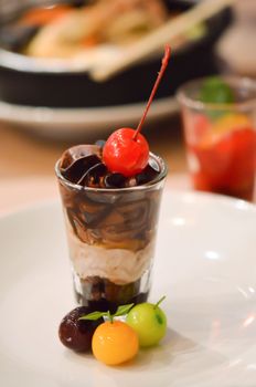 A layered chocolate , garnished with cherries and a delicate marchpane  fruit 