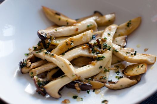 Fried sliced king oyster mushrooms with butter, onions and parsley