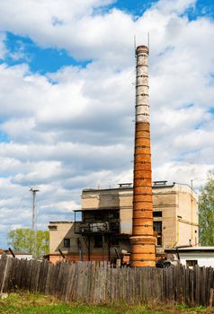 Boiler house with high stack and wooden fence in front