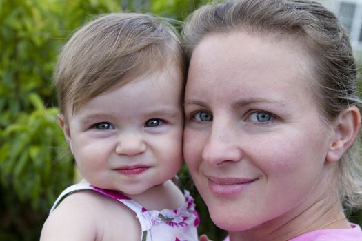 Mother and Daughter headshot. Mother looking at camera with a secure, trusting feelings. Smilar impression on 11 months baby.