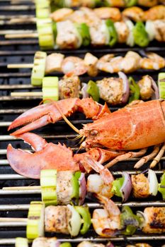Lobster and fish skewers are on the barbecue.