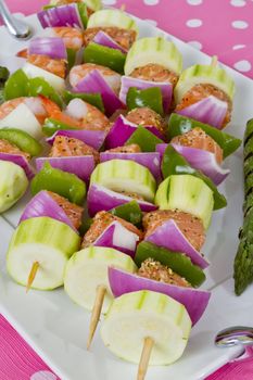 Salmon cubes and Shrimp complimented with vegetables on skewers. Ready to cook. Red onions, zucchini, green peppers and asparagus.