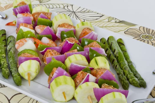 Salmon cubes and Shrimp complimented with vegetables on skewers. Ready to cook. Red onions, zucchini, green peppers and asparagus.