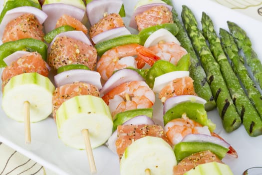 Salmon cubes and Shrimp complimented with vegetables on skewers. Ready to cook. Red onions, zucchini, green peppers and asparagus.
