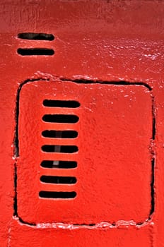 Old metal door with vents, painted with red paint