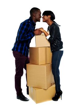 Cardboard boxes in between couple holding hands and about to kiss