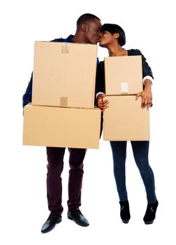 African couple holding cardboard boxes and kissing. Full length portrait