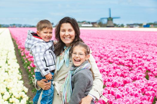 Mother with her child walks between of the white and purple tulips field