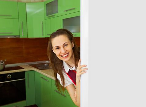 Young happy woman on kitchen near the refrigerator