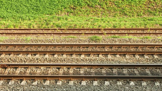 Parallel rail lines on the background of roadside covered with vivid grass