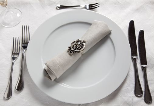 Table setting with plate, knives, forks napkin with ring on linnen tablecloth