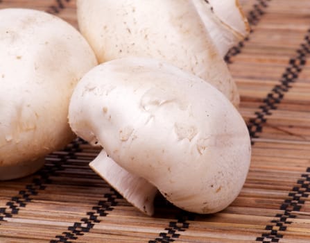 Raw White Champignon Mushroom closeup on straw mat background