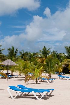 stunning beach with chairs and coconut umbrella on a tropical resort in Antigua (gorgeous blue sky with clouds)