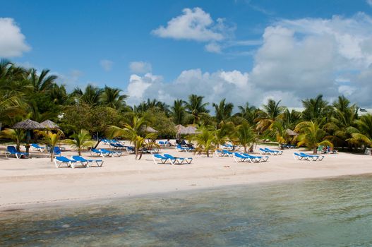 stunning beach with chairs and coconut umbrella on a tropical resort in Antigua (gorgeous blue sky with clouds)