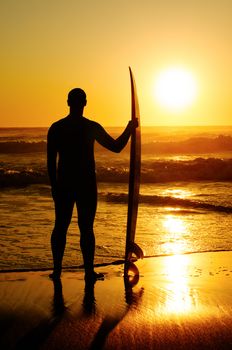 A surfer watching the waves at sunset in Portugal.