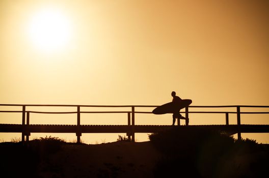 A surfer running to the beach at sunset in Portugal.