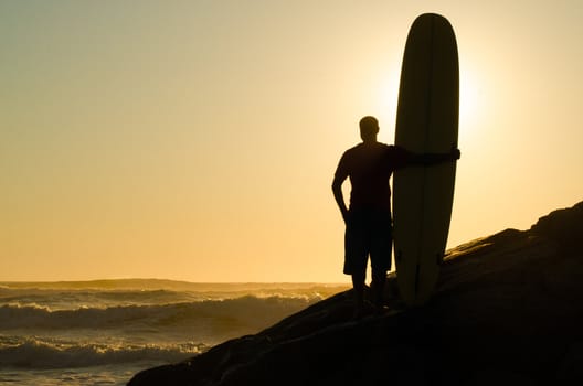 A long boarder watching the waves at sunset in Portugal.