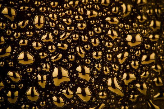 Golden liquid drops on black background.