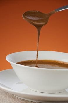 Chocolate mousse falling from spoon to white bowl.
