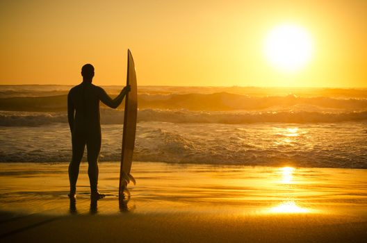 Surfer watching the waves at sunset in Portugal.