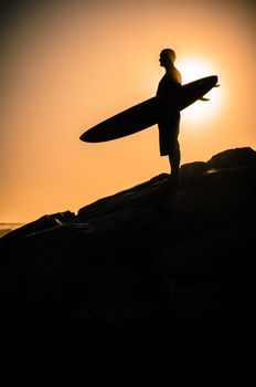 A surfer watching the waves at sunset in Portugal.