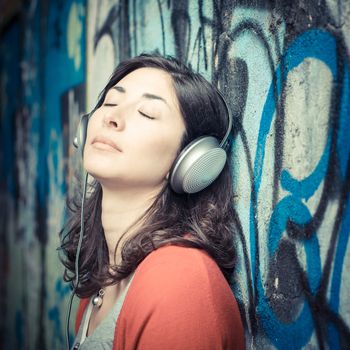 Beautiful stylish woman listening to music in the street 