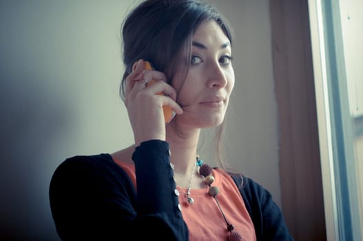 beautiful woman at home at the phone near window