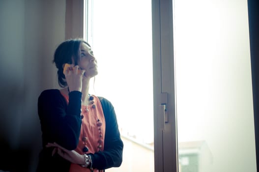 beautiful woman at home at the phone near window