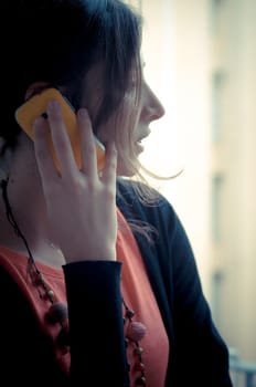 beautiful woman at home at the phone near window