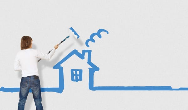 Young man with a paintbrush and family picture on the wall