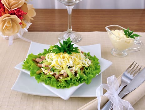 Salad with ham, cucumber, egg under the chips in the leaves of lettuce