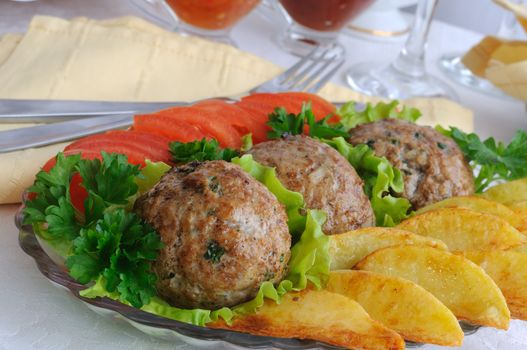 Meatballs with greens on salad leaves with potatoes and tomatoes