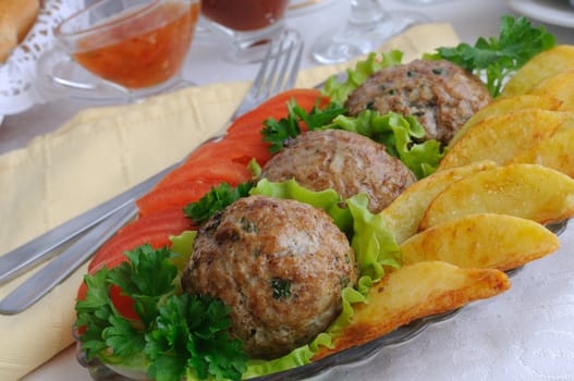 Meatballs with greens on salad leaves with potatoes and tomatoes