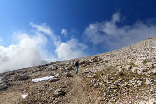 woman walks on alpine pathway - Rosetta mount, Trentino, Italy