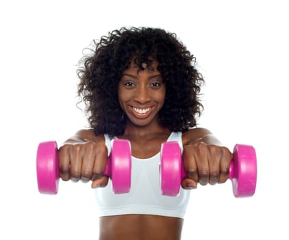 Portrait of curly haired african fit woman holding pink dumbbells