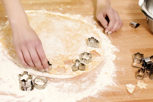 female hands pressing christmas molds in dough