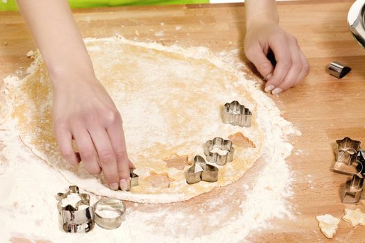 closeup of hands pressing christmas molds in dough on a kitchen table