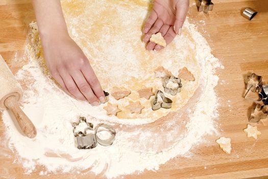 closeup of hands pressing christmas molds in dough on a kitchen table