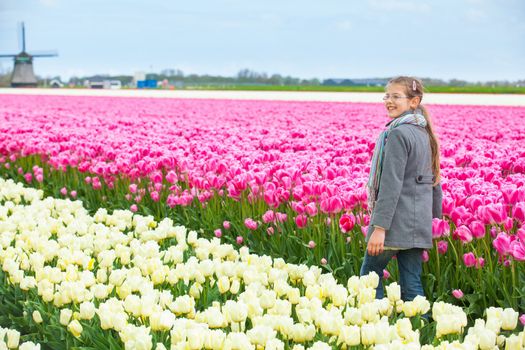 Girl walks between of the colorful tulips field