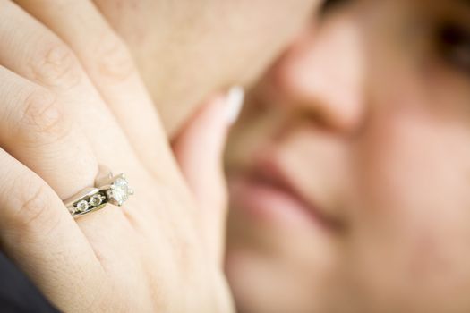 Young Female Hand with Engagement Ring Touching Fiance's Face with Selective Focus on the Ring.