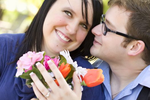 Attractive Young Man Gives Flowers to His Fiance Wearing the Engagement Ring.