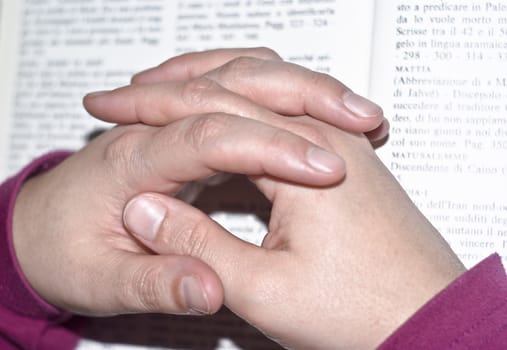 Hands in prayer of woman over the bible.