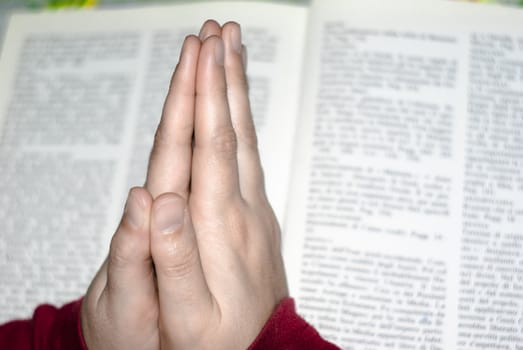 Hands in prayer of woman over the bible.