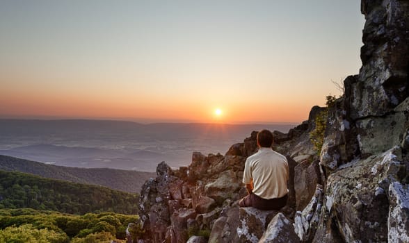 Back view of man watching sunset from rocky summit of Stony Man on Skyline Drive in Virginia