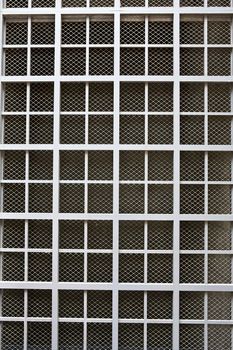 Dull silver color metal bars over screen covering building window